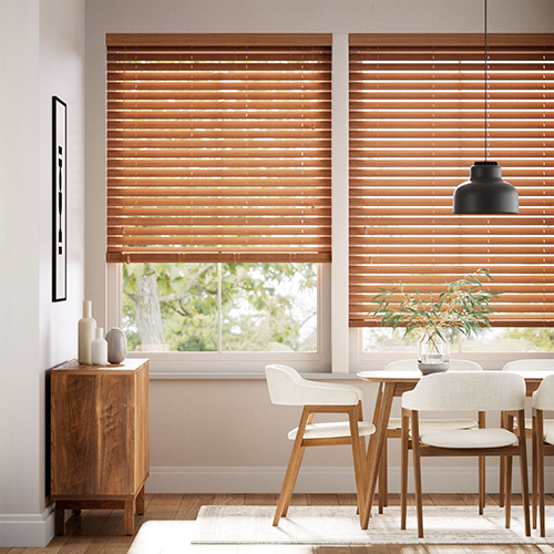 A dining area with made to measure Venetian blinds, white chairs, a wooden table, and a sideboard, bathed in natural light.