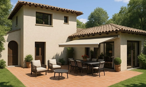 A Mediterranean-style house with tan rendered walls, a tiled roof, and a shaded patio featuring outdoor furniture, table, and chairs, surrounded by green grass and trees under a clear blue sky.