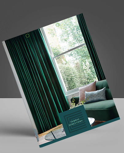 A catalogue titled Fabric Directory featuring a living room with tall green curtains, a large window, a green sofa with cushions, and trees visible outside.