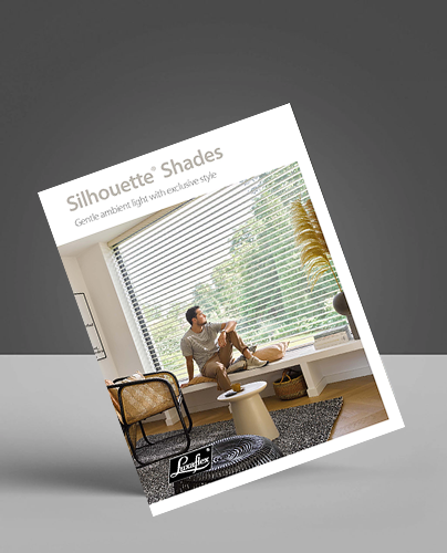 A brochure for Silhouette Shades features a man sitting on a wide windowsill in a bright room with large windows covered by horizontal blinds, surrounded by modern furniture and greenery outside.