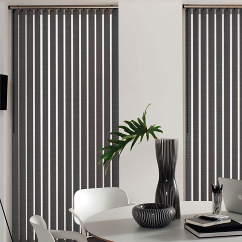 A modern dining area features a round table with white chairs, a striped vase with a leafy green plant, and made-to-measure vertical blinds covering two large windows, allowing light to filter through.