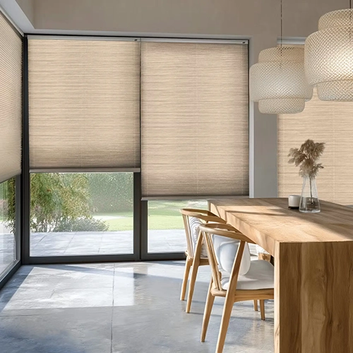 A modern dining room with large windows covered by beige roller blinds, a wooden table with four chairs, and decorative pendant lights and dried flowers in a vase. Sunlight filters through the blinds.