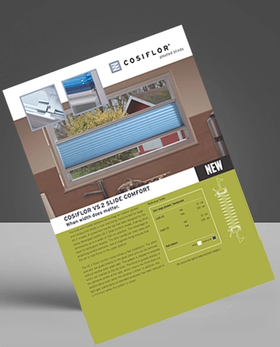 A tilted Cosiflor brochure displaying a window with blue VS2 Slide Comfort Blinds, product images, text, and diagrams on a white and green background. The brochure advertises the innovative VS2 Slide Comfort window blind system.
